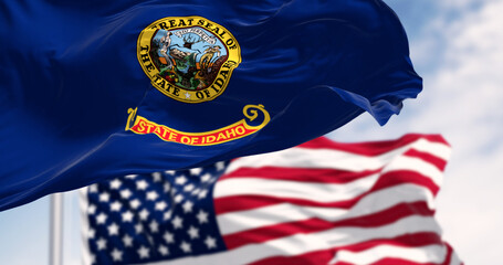 The Idaho state flag waving along with the national flag of the United States of America on a clear day.