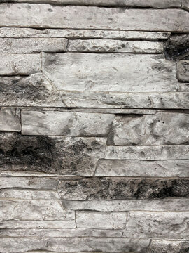 The wall is lined with decorative stone, beautiful seams, background. For the facade of the house, fence
