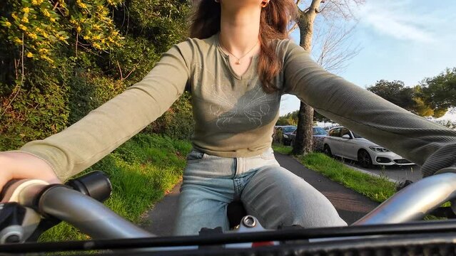 LD Teenage girl riding a bike on a bike path in a city at sunset