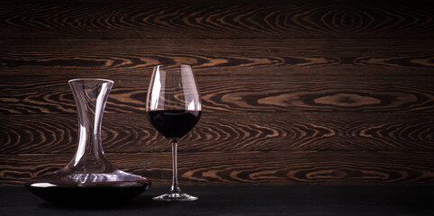 Decanter and glass with red wine on wooden rustic background