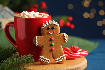 Tasty gingerbread man cookie and cocoa with marshmallows on blue wooden table, closeup