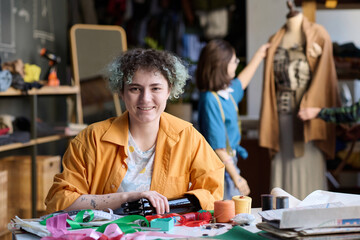 Portrait of young woman with arm prosthetic smiling at camera in atelier workshop copy space