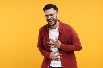 Handsome young man laughing on yellow background