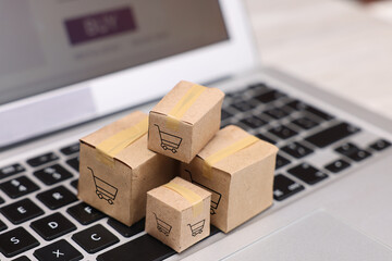 Fototapeta premium Internet store. Small cardboard boxes with shopping carts on laptop, closeup