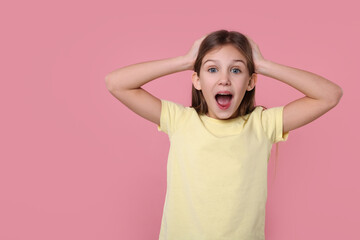 Portrait of surprised girl on pink background. Space for text