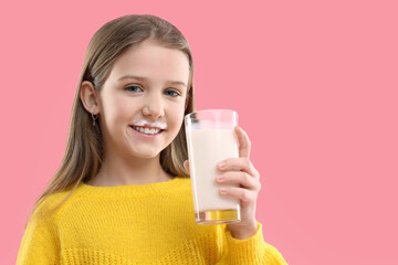 Happy little girl with milk mustache holding glass of tasty dairy drink on pink background. Space for text