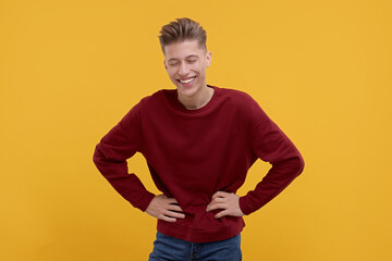 Portrait of young man laughing on orange background