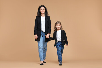 Fototapeta premium Beautiful mother with little daughter on beige background