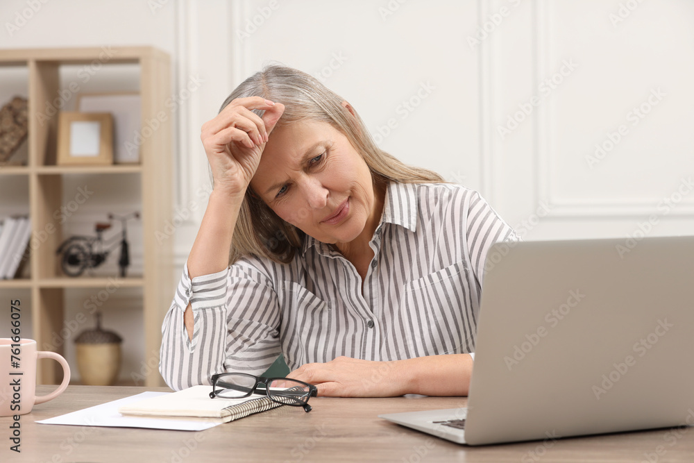 Sticker Menopause. Woman suffering from headache at wooden table indoors