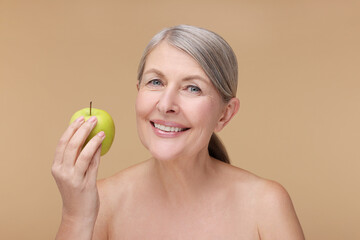 Beautiful woman with fresh apple on beige background. Vitamin rich food