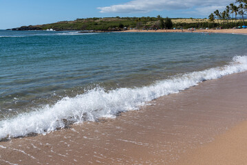 Waves breaking on sandy beach in calm bay near the ocean