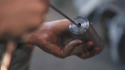 An employee is engaged in processing a metal product with a hand tool at the final stage of production at a production or metallurgical plant