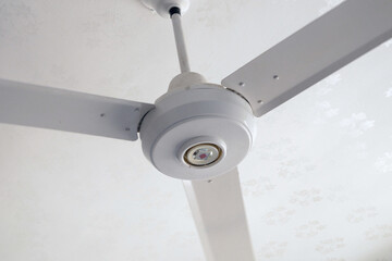 Silver ceiling fan rotating on white background, room cooling and ventilation concept