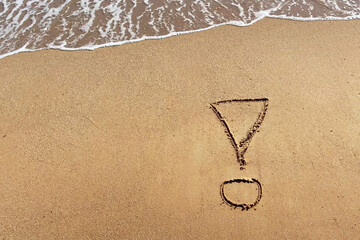 Exclamation mark writing on beach sand on blue water waves background. Top view.