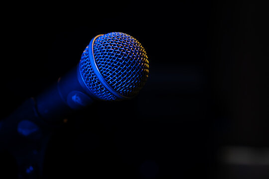 Close-up of a microphone with blue backlight in a music studio, at a concert in the dark, copy space