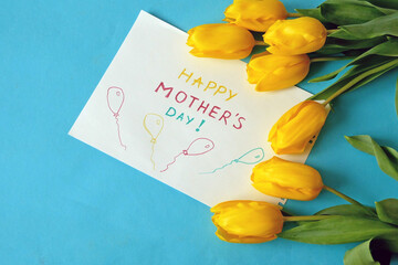 hands put a Happy Mother's Day card and flowers on the table, preparing for congratulations on Mother's Day