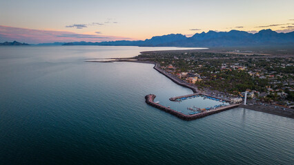 drone fly above Loreto Baja California Sur Mexico old colonial town with sea gulf ocean and mountains desert landscape at sunset - obrazy, fototapety, plakaty