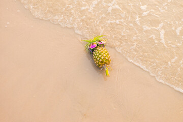 Funny pineapples in stylish sunglasses on the sand..