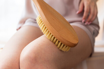 Her delicate hand grips the wooden brush as she gently caresses her leg in a soothing gesture. The...