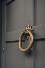 Metal door knocker on a wooden front door of a house.