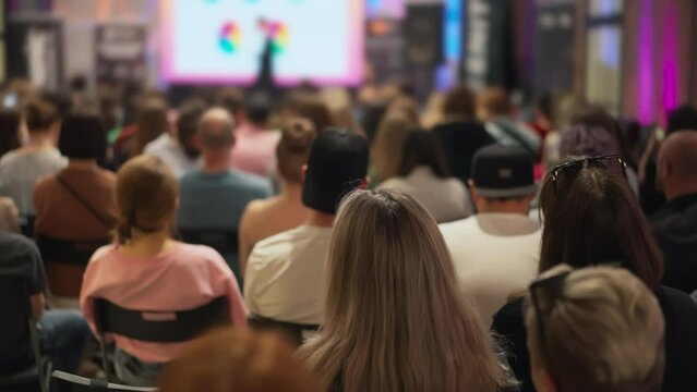 Group of young entrepreneurs at a tech innovation presentation, background with female speaker. A snapshot of technology engagement. Good for illustrating young minds exploring new technologies.