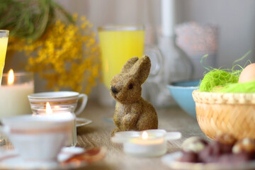 Easter eggs in the basket, bowl of cookies, chocolate pralines, Easter bunny figurine, cups of tea,...