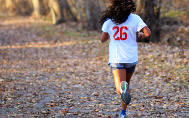 Teenage girl running on a path fuill of leaves training for distance running races