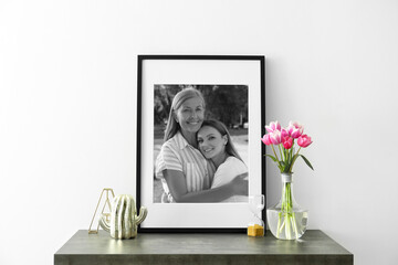 Black and white family portrait of mother and daughter in photo frame on table near white wall