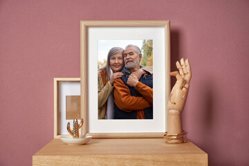 Family portrait of man and woman in photo frame on table near color wall
