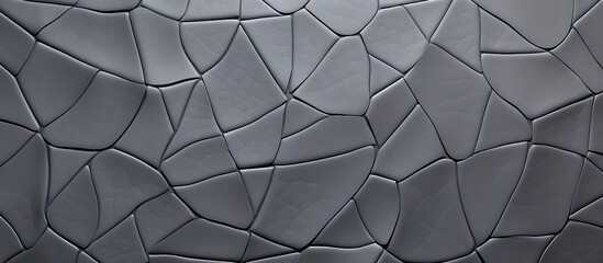 A closeup monochrome macro photograph of a gray tile wall with a geometric pattern featuring circles and triangles in a symmetrical layout