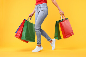 Woman with shopping bags on yellow background, closeup