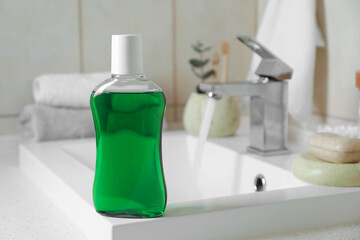 Fresh mouthwash in bottle on sink in bathroom, closeup. Space for text