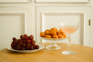 A glass of pink wine and a plate of cookies on a wooden table