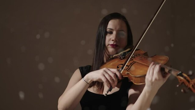 Portrait Of Talented Woman Playing Violin In Studio With Amazing Snow Flying Up, Slow Motion