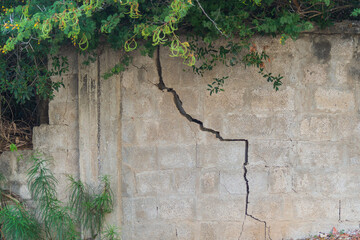 Crack in a concrete fence made of cement blocks, appeared as a result of soil shrinkage in area of...