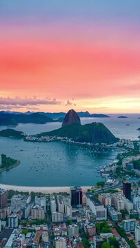 View of sunset on Rio De Janeiro looking towards Sugarloaf Mountain and the Atlantic ocean, Brazil. Aerial vertical drone hyperlapse.