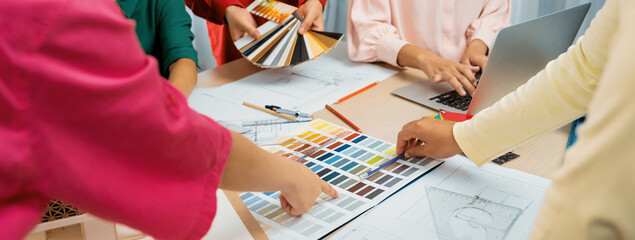 Professional designer team brainstorms material colors, while the project manager suggests a suitable color at meeting table with architectural equipment and color palette scatter around. Variegated. - obrazy, fototapety, plakaty
