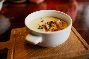 A bowl of soup is placed on a wooden cutting board, showcasing a simple yet comforting meal.