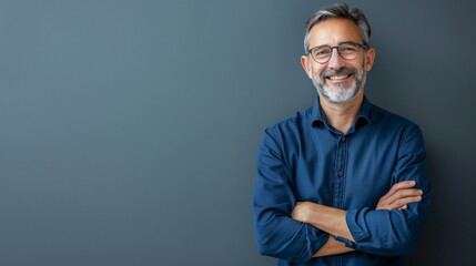 Portrait mature businessman smiling while standing against blue wall - Powered by Adobe