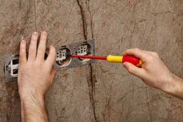 Man installing electrical outlet on the wall with a screwdriver - 761723420