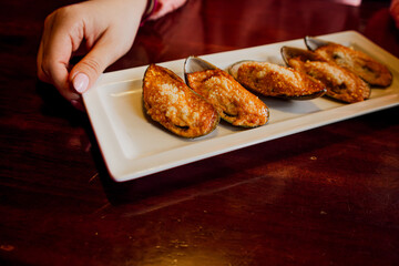 Baked mussels with sauce and cheese on a white plate