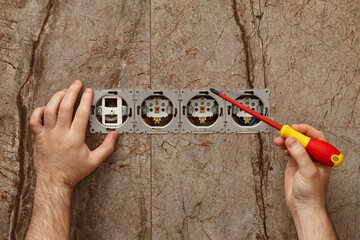 Man installing electrical outlet on the wall with a screwdriver - 761723479