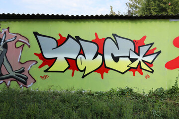 The old wall decorated with paint stains in the style of street art culture. Colorful background of full graffiti painting artwork with bright aerosol outlines on wall. Colored background texture