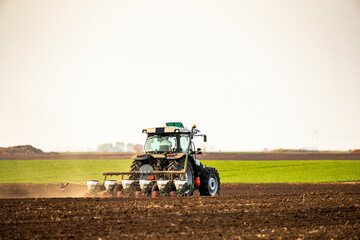 Obraz premium Modern tractor seeding, planting agricultural field at dusk