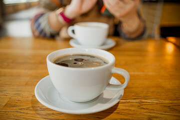 Two cups of coffee resting on a wooden table, representing a cozy coffee break moment in a comfortable setting.