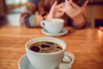 Two cups of coffee resting on a wooden table, representing a cozy coffee break moment in a comfortable setting.