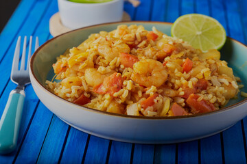 Spicy prawn curry with rice and garnished with a wedge of lime.