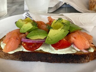 Toast topped with cream sauce, salmon, tomato and avocado