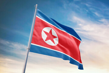 Waving flag of North Korea in blue sky. North Korea flag for independence day. The symbol of the state on wavy fabric.