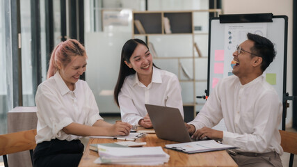 Three people are sitting around a table, smiling and laughing
